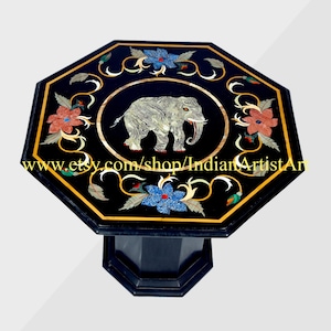 Pode incluir: Mesa octogonal de mármore preto com um design de elefante incrustado e acentos florais. A mesa tem uma base de mármore preto.