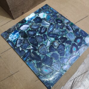 Pu&ograve; includere: Una piastrella quadrata realizzata in agata blu con un supporto in resina epossidica verde. La piastrella &egrave; composta da molti pezzi di agata diversi, ognuno con un motivo unico. La piastrella &egrave; perfetta per l'uso come piano di lavoro, schienale o parete di accento.