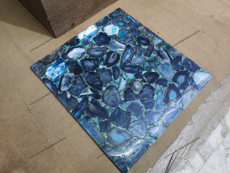 Pu&ograve; includere: Una piastrella quadrata realizzata in agata blu con un supporto in resina epossidica verde. La piastrella &egrave; composta da molti pezzi di agata diversi, ognuno con un motivo unico. La piastrella &egrave; perfetta per l'uso come piano di lavoro, schienale o parete di accento.