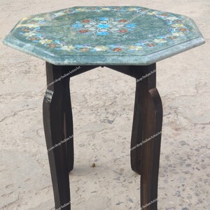 May include: A small, octagonal side table with a green marble top inlaid with a floral design in shades of blue, red, and yellow. The table has dark brown wooden legs. The table is approximately 24 inches tall.