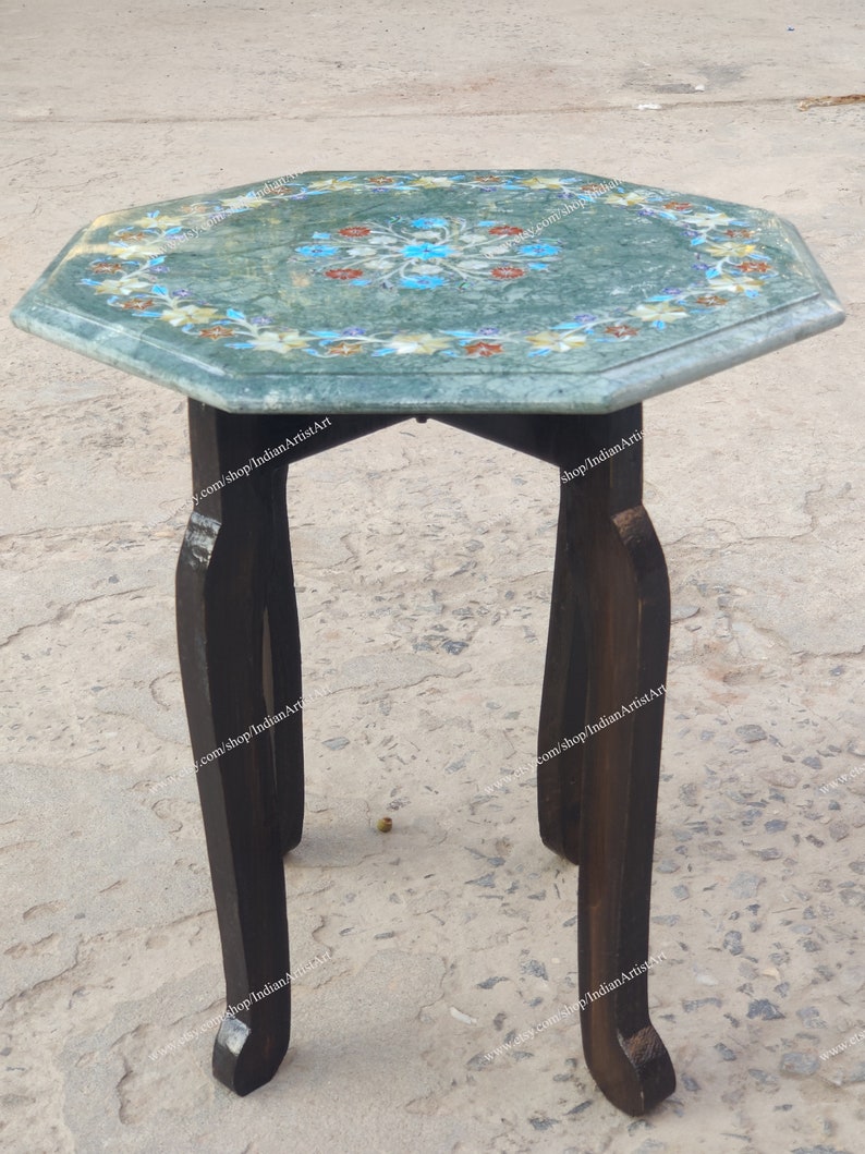 May include: A small, octagonal side table with a green marble top inlaid with a floral design in shades of blue, red, and yellow. The table has dark brown wooden legs. The table is approximately 24 inches tall.