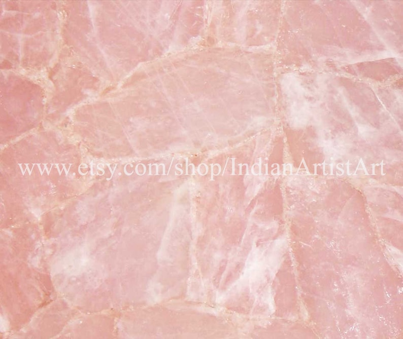 May include: A close-up of a pink rose quartz slab with a natural, irregular, and textured surface. The slab is made up of many smaller pieces of rose quartz that have been joined together.