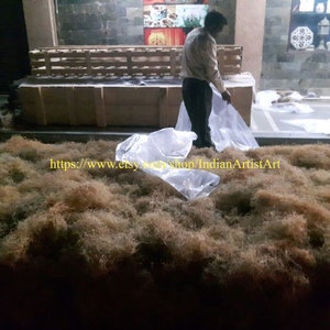 May include: A large pile of dried brown fibers, likely for use in crafts or floral arrangements. The fibers are spread out on a concrete floor, with a few plastic bags nearby. The text "https://www.etsy.com/shop/IndianArtistArt" is visible in the lower left corner of the image.