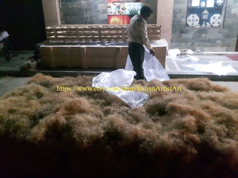 May include: A large pile of dried brown fibers, likely for use in crafts or floral arrangements. The fibers are spread out on a concrete floor, with a few plastic bags nearby. The text "https://www.etsy.com/shop/IndianArtistArt" is visible in the lower left corner of the image.