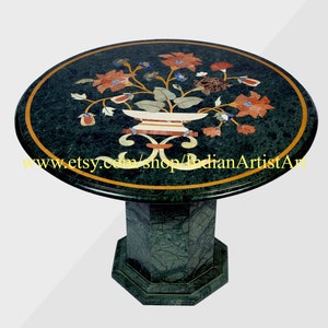 Pode incluir: Mesa redonda de mármore verde com um design de incrustações florais. A superfície da mesa apresenta um vaso com flores em tons de vermelho, laranja e verde. A mesa tem uma base de pedestal.