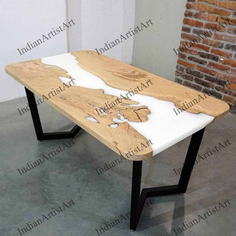 Puede incluir: Una mesa de comedor de madera natural y blanca con un dise&ntilde;o &uacute;nico de r&iacute;o de resina epoxi. La mesa tiene una base de metal negro con un dise&ntilde;o geom&eacute;trico.