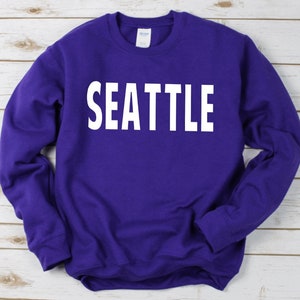 May include: Purple sweatshirt with white text that reads "SEATTLE".