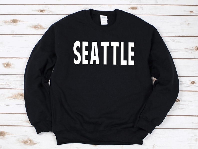 May include: Black sweatshirt with the word "SEATTLE" printed in white on the front.