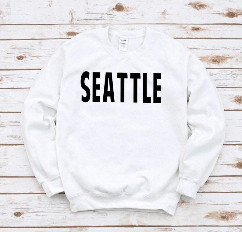 May include: White sweatshirt with black text that reads "SEATTLE".