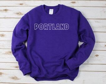 May include: Purple sweatshirt with white outlined text that reads "PORTLAND".