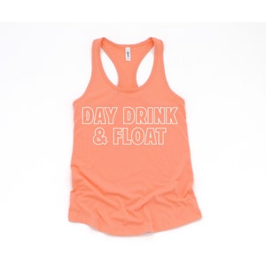 May include: A coral-colored tank top with the text "DAY DRINK & FLOAT" in white outlined letters.
