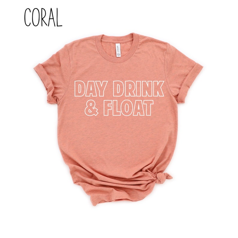 Op de afbeelding: Koraal gekleurd T-shirt met de tekst "DAY DRINK & FLOAT" in witte omrande letters.