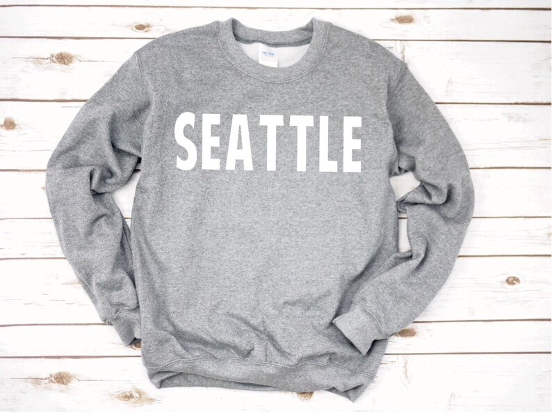 May include: A grey sweatshirt with the word "SEATTLE" printed in white on the front.