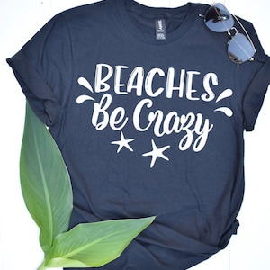 May include: A dark blue t-shirt with the text "Beaches Be Crazy" in white lettering and two white starfish.