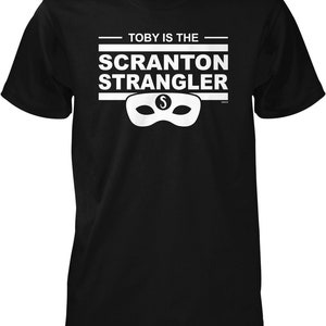 May include: Black t-shirt with white text that reads "Toby is the Scranton Strangler" and a white mask with an "S" on it.