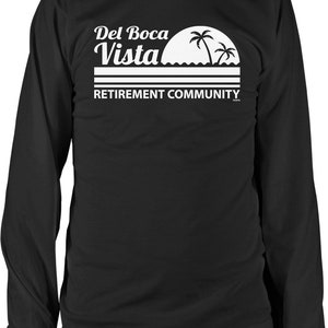 May include: Black long-sleeve t-shirt with a white graphic of a sunset with palm trees and the text "Del Boca Vista Retirement Community".