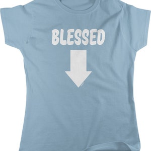 May include: Light blue t-shirt with the word "BLESSED" in white, above a white downward-pointing arrow. The shirt is a short-sleeved crew neck style.
