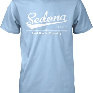 May include: Light blue t-shirt with a white graphic design that says "Sedona, Arizona, Red Rock Country".