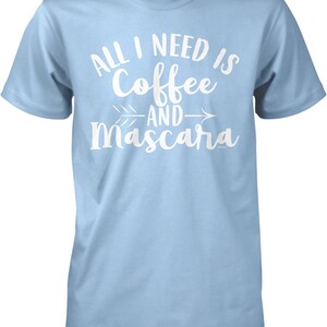 May include: Light blue t-shirt with white text that reads "All I need is coffee and mascara" with an arrow pointing to the right.