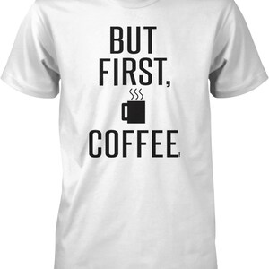 May include: White t-shirt with black text that reads "But first, coffee." and a black coffee cup icon with steam coming from it.