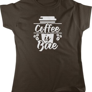May include: A brown t-shirt with a white graphic design of a coffee cup with the text "Coffee is Bae" and coffee beans.