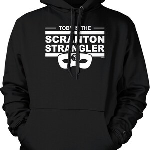 May include: Black hooded sweatshirt with the text "TOBY IS THE SCRANTON STRANGLER" in white, along with a white mask graphic. The sweatshirt has a drawstring hood and a front pocket.