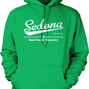 May include: Green hooded sweatshirt with the word "Sedona" in white script across the chest, along with "Arizona" and "Red Rock Country" in white block letters. The sweatshirt has a front pocket and a drawstring hood.