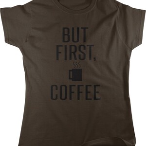 May include: A brown t-shirt with the text "But first, coffee" in black lettering. A stylized coffee cup with steam rising from it is between the words "first" and "coffee".
