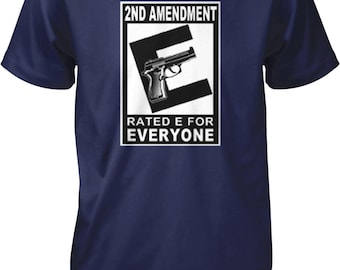May include: A navy blue short-sleeve t-shirt featuring a white rectangular graphic on the chest. The graphic displays the text 2ND AMENDMENT at the top, a large black letter E with a handgun illustration, and the text RATED E FOR EVERYONE below.