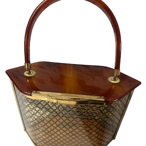 May include: Vintage handbag with a brown, arched handle and a tortoiseshell-patterned top. The body of the bag is a gold-toned, mesh-like material, and the hardware is gold-colored. A classic, retro accessory.