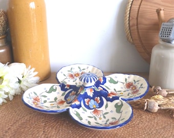 May include: A white ceramic serving dish with four sections and a central dome. The dish is decorated with blue, green, and orange floral patterns.