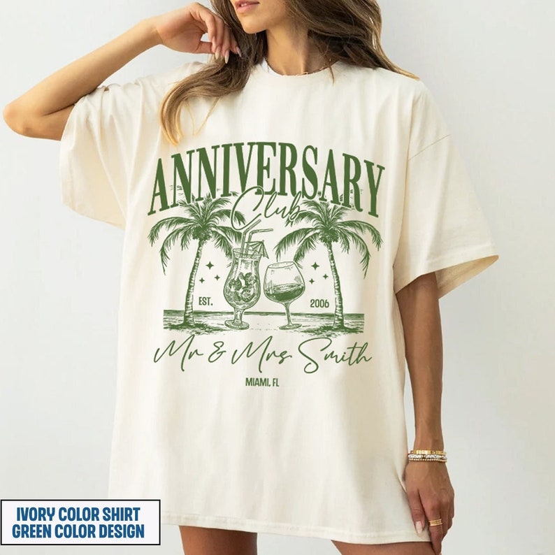 K&ouml;nnte beinhalten: Ein T-Shirt in Elfenbein mit einem gr&uuml;nen Design, das Palmen, Cocktails und den Text "Anniversary Club Est. 2006 Mr & Mrs Smith Miami, FL" zeigt.