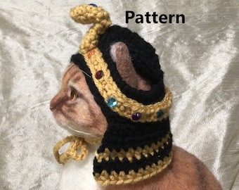 May include: A crocheted cat costume with a gold crown and a snake on top. The costume is black and gold with a black and gold striped collar. The costume is for a cat and is a PDF crochet pattern.
