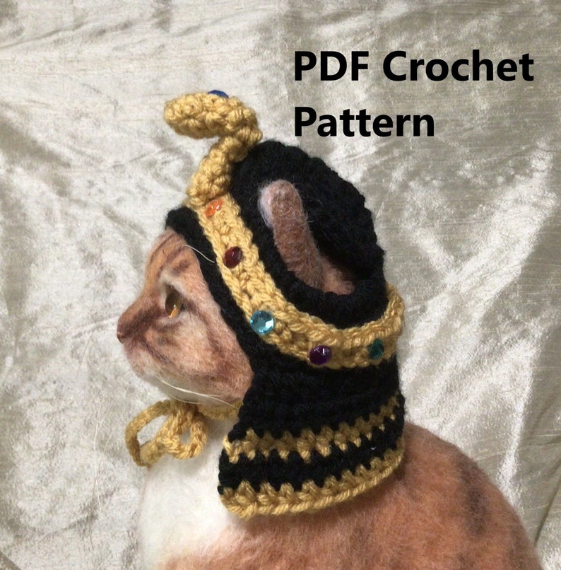 K&ouml;nnte beinhalten: Ein geh&auml;keltes Katzenkost&uuml;m mit einer goldenen Krone und einer Schlange oben drauf. Das Kost&uuml;m ist schwarz und gold mit einem schwarz-gold gestreiften Kragen. Das Kost&uuml;m ist f&uuml;r eine Katze und ist ein PDF-H&auml;kelmuster.