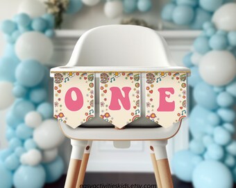 Peut inclure: Une chaise haute blanche avec une bannière colorée qui dit "ONE" en lettres roses. La bannière a un thème rétro des années 70 avec des fleurs, des signes de paix et des notes de musique.