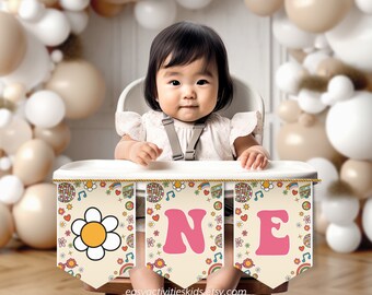 Peut inclure: Un bébé est assis dans une chaise haute avec une bannière colorée qui dit "ONE" en lettres roses. La bannière a un thème des années 1970 avec des marguerites, des signes de paix, des arcs-en-ciel et des notes de musique.