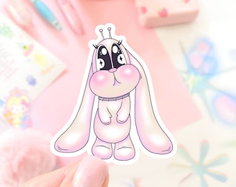 May include: A pink and white cartoon bunny sticker with large eyes and a sparkly design. The bunny has long ears and is standing on its hind legs.