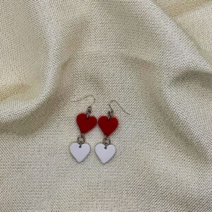 May include: A pair of dangle earrings with two hearts on each earring. The top heart is red and the bottom heart is white.