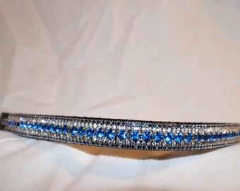 May include: A black headband adorned with a central row of vibrant blue crystals, flanked by clear crystals. The crystals are set in a silver-toned band. This accessory is designed for comfortable wear.