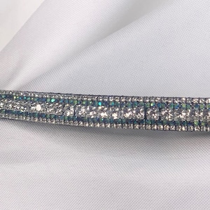 May include: A black leather headband with a row of silver and teal rhinestones.