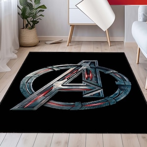 May include: Black area rug with a silver and red Avengers logo. The logo is a stylized "A" inside a circle.