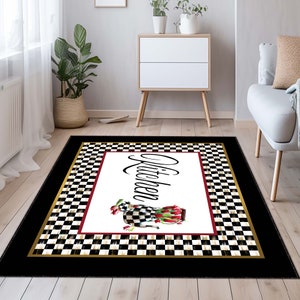May include: A rectangular area rug featuring a central white panel with the word Kitchen in black script, accompanied by a checkered teapot filled with red tulips. The design includes a black and white checkered border and a solid black edge.