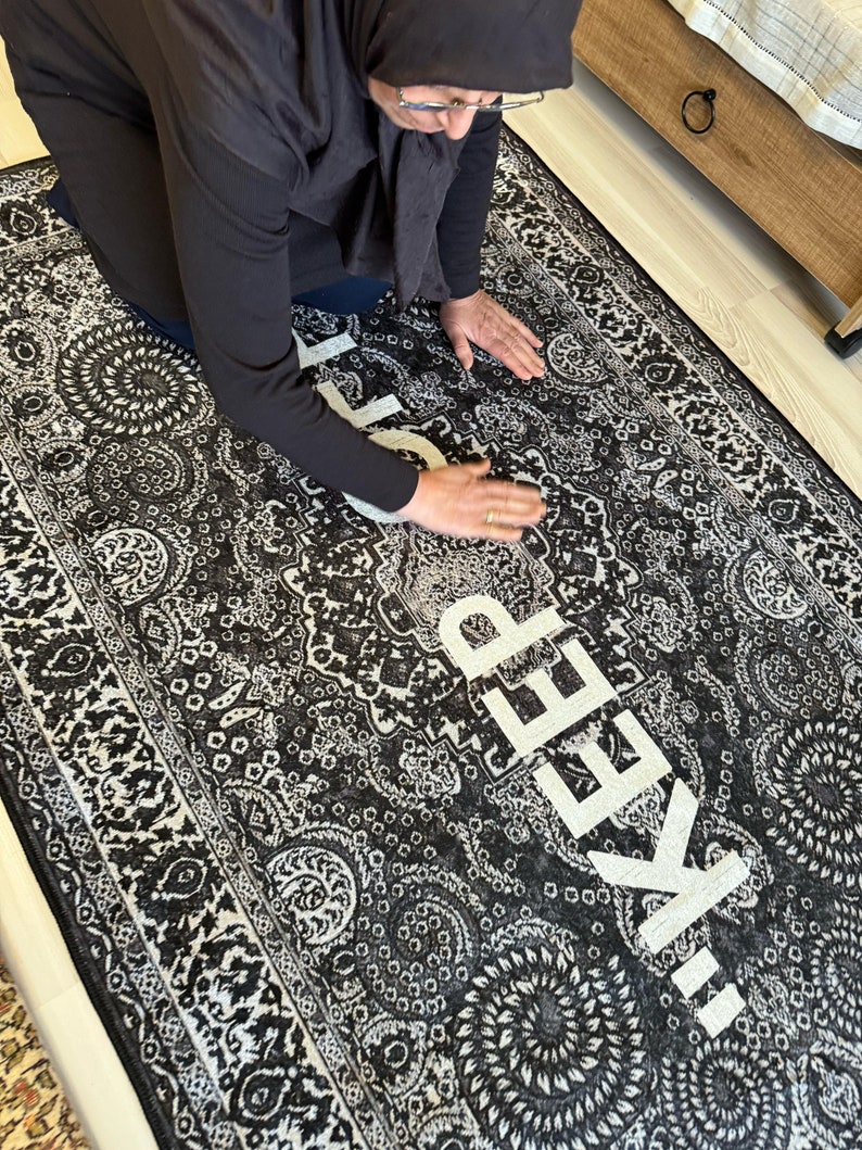 May include: A black and white patterned rug with the words "!KEEP" written in white letters.