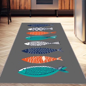 May include: A gray kitchen rug with a pattern of colorful fish. The fish are in various shades of blue, orange, and green. The rug is perfect for adding a touch of whimsy to any kitchen.