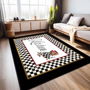 May include: A rectangular area rug featuring a central white panel with the word Kitchen in black script, a checkered teapot filled with red tulips, and a red border. The rug has a black and white checkered frame with a gold trim and black border.