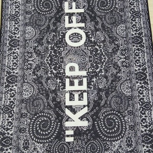 May include: Black and white rug with a traditional paisley pattern. The text "KEEP OFF!" is printed in white in the center of the rug.