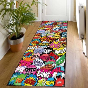 May include: A colorful doormat with a comic book theme. The doormat features a black background with various colorful speech bubbles containing words like "BOOM!" "POW!" and "ZAP!"