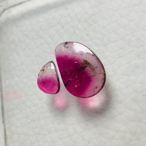 May include: Two pink and white gemstones with a teardrop shape. The larger gemstone is about 1 inch long and the smaller gemstone is about 1/2 inch long.