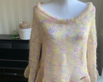May include: A soft, pastel-colored knitted sweater with a ruffled hem. The sweater is made of a fuzzy yarn in shades of yellow, pink, and purple.