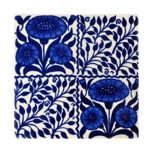 May include: A blue and white ceramic tile with a floral pattern. The tile features stylized flowers with blue petals and white centers, surrounded by blue leaves on a white background.